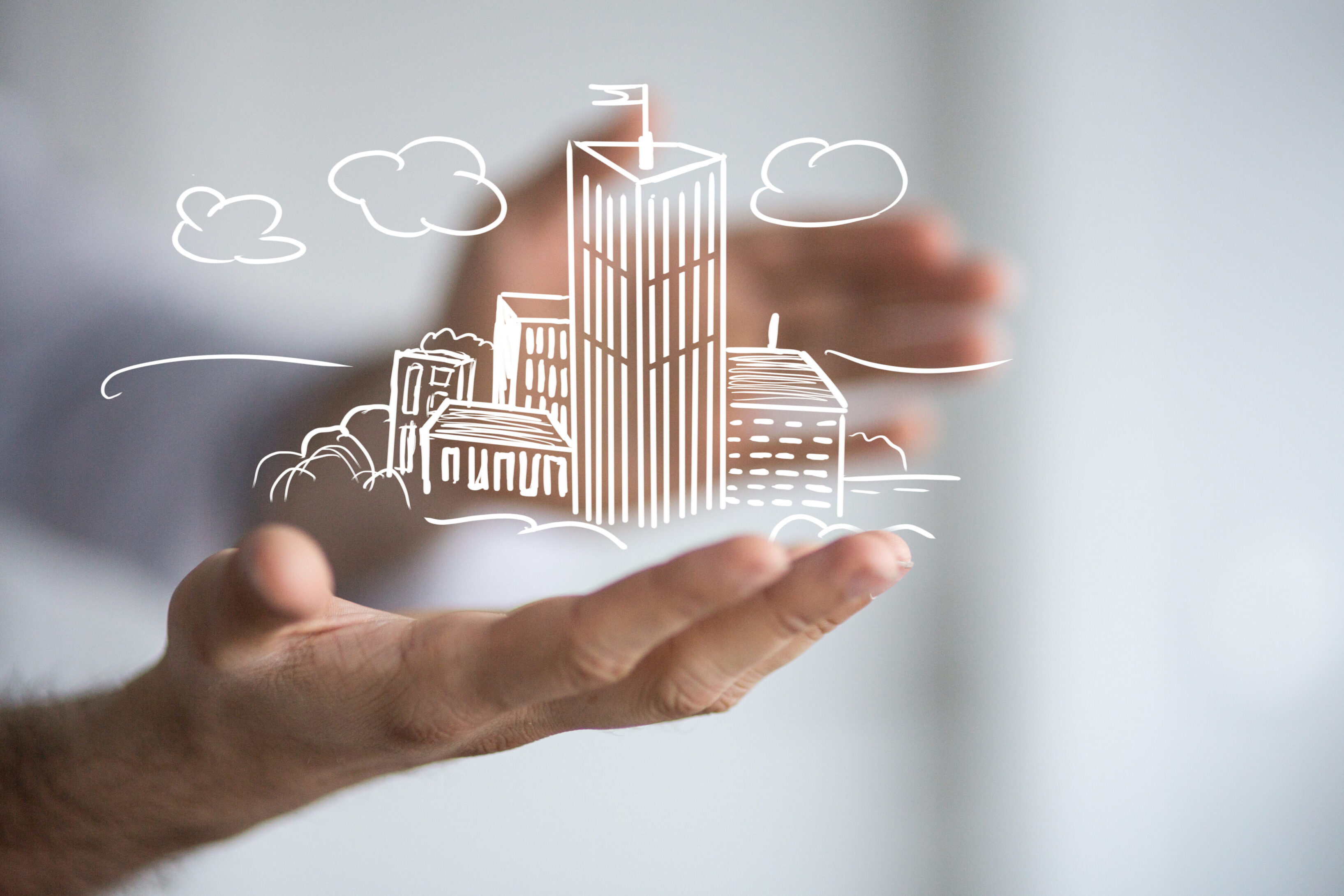 Hand holding a digital cityscape with buildings and clouds.