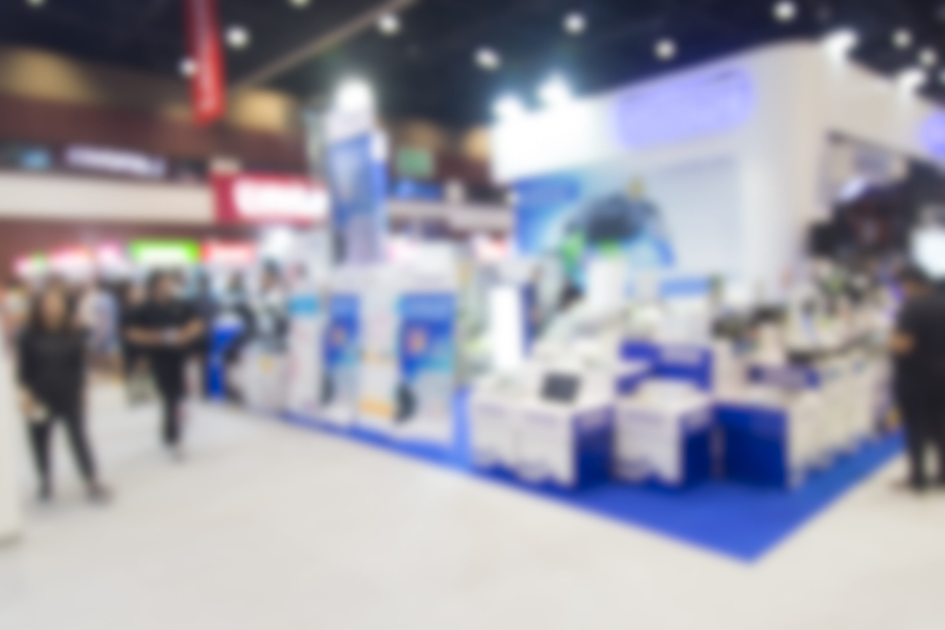 Busy exhibition booth showcasing technology products with people interacting.