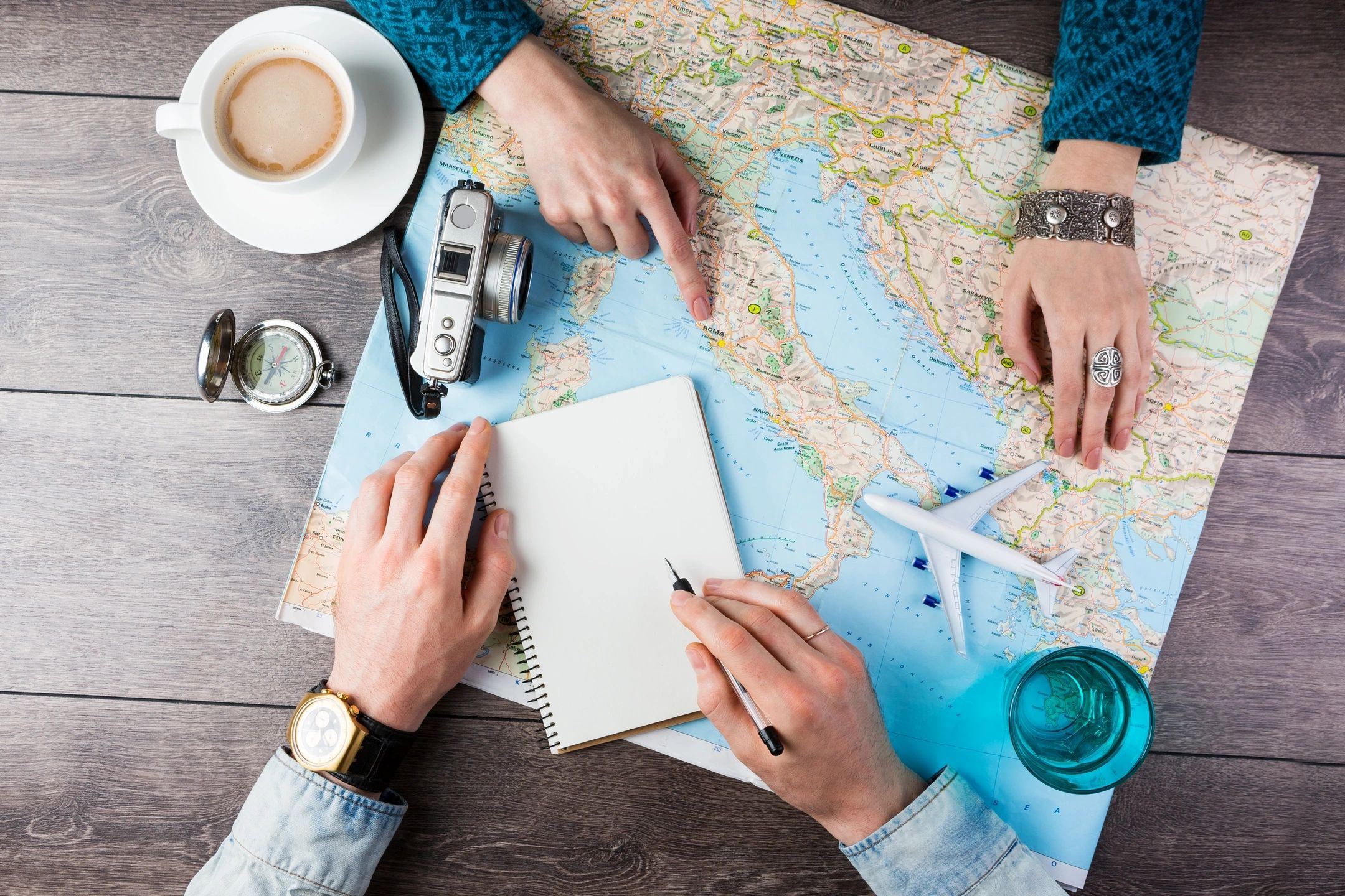 Couple planning a trip with map, notebook, and travel essentials.